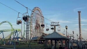 Une montagne russe avec une grande roue en arrière-plan, une haute tour et un kiosque.