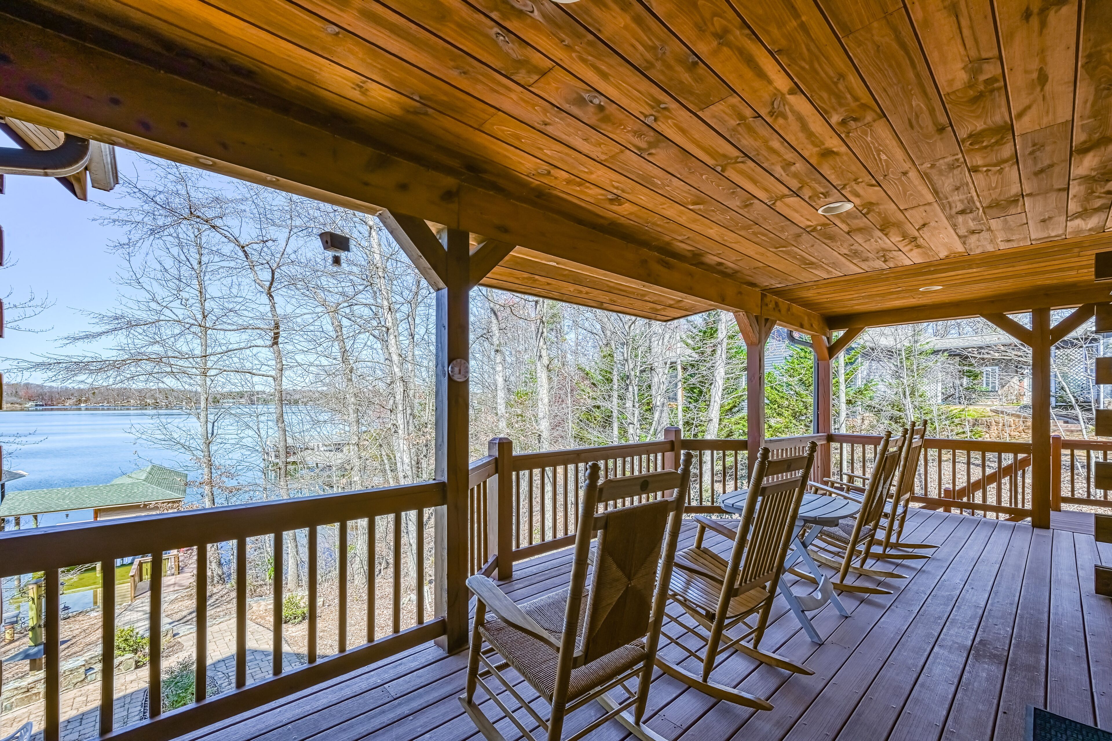 Une terrasse en bois offrant une vue sur un lac et des arbres.