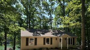 A small cabin with a single door and windows, surrounded by trees and a gravel path. - Humble Hideaway - Inviting lakefront home with firepit, balcony & W/D - dog-friendly (Moneta)