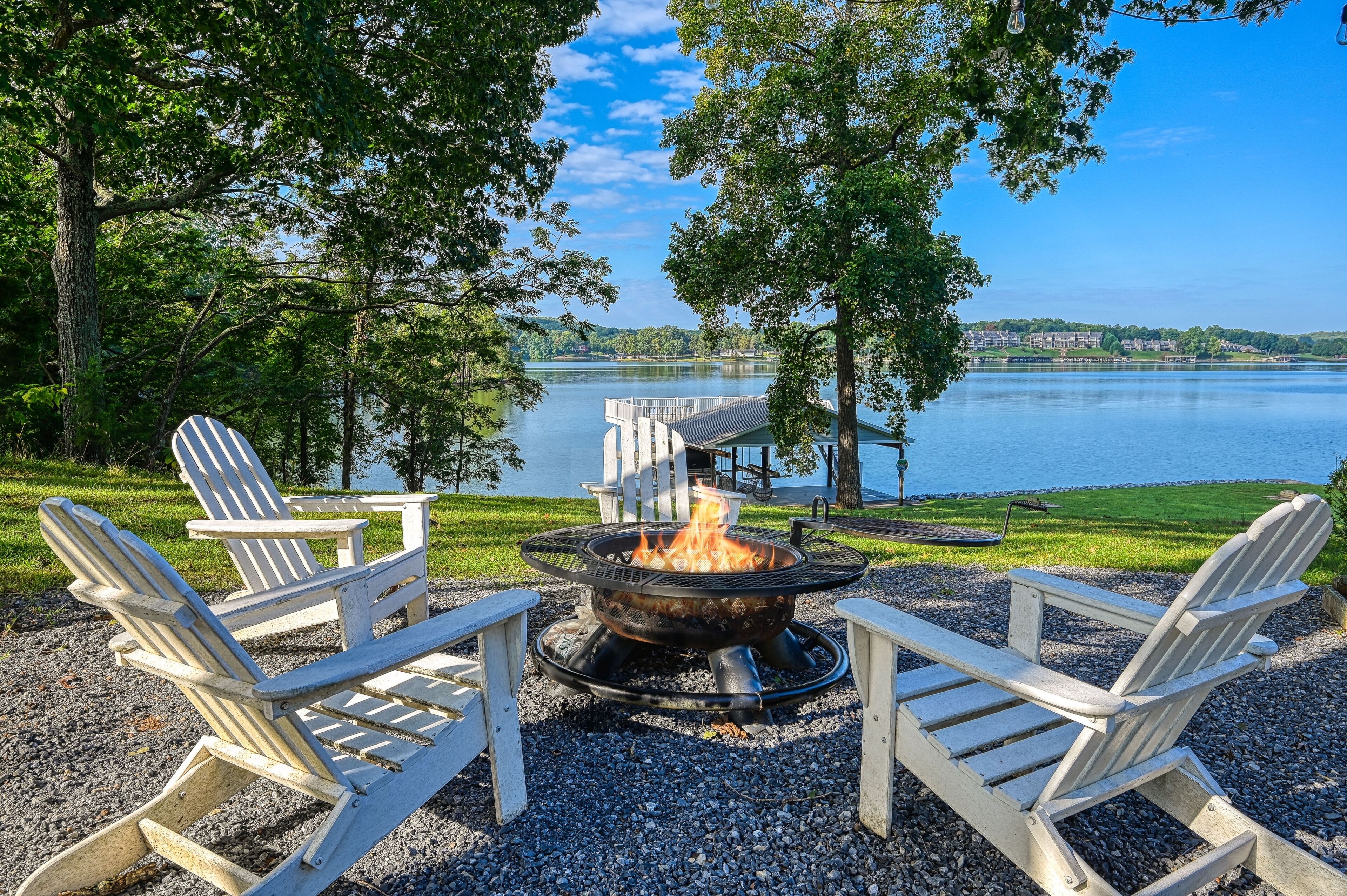 Zona de estar al aire libre junto al lago, con sillas Adirondack y una chimenea.