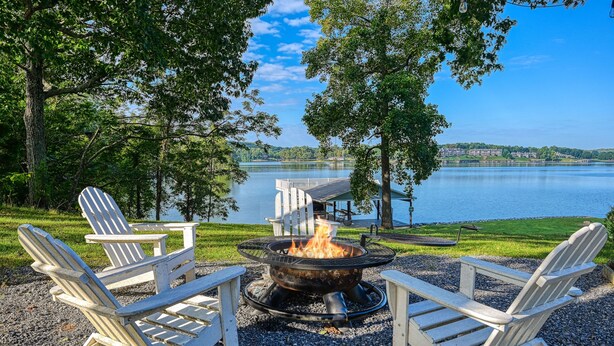 Un espace extérieur aménagé au bord du lac, avec des chaises Adirondack et un foyer.