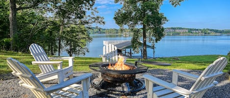 Zona de estar al aire libre junto al lago, con sillas Adirondack y una chimenea.