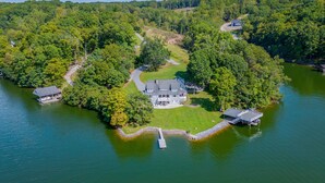 Vue aérienne d’une propriété au bord du lac, avec une grande maison, un quai et un bateau.