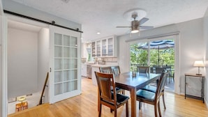 Une cuisine spacieuse avec des meubles blancs et un coin repas comprenant une table et des chaises en bois.