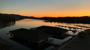 Un port de plaisance avec des bateaux amarrés, un lac paisible et un coucher de soleil en arrière-plan.