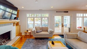 A living room with a fireplace, a sofa, a coffee table, and a television. - Bears Den at Acorn Dr - Spacious pet friendly Cottage with balcony, dock, and hot tub (Moneta)
