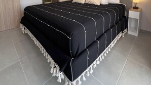 Ein Schlafzimmer mit einem großen Bett, einem Nachttisch mit Lampe, einer Holztür und einem Spiegel.