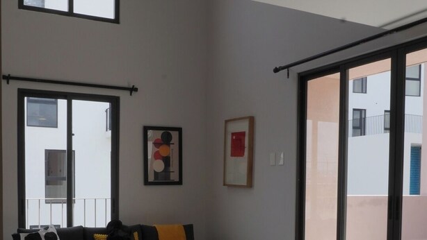 A modern living room with a sofa, a small round table, and a view through large sliding glass doors to an outdoor balcony. - Mr. W | Moderno departamento de 2 pisos y terraza (Guadalajara)