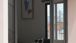 A modern apartment with a glass door leading to a balcony, a small round table, a sofa with a polka dot cushion, and a framed abstract painting. - Mr. W | Moderno departamento de 2 pisos y terraza (Guadalajara)