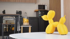 Une cuisine équipée d’un four à micro-ondes, d’un four traditionnel et d’une table sur laquelle est posé un ballon en forme de chien jaune.