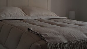 A bed with a quilted headboard, a plain wall, and a bedside table with a lamp. - Mr. W | Moderno departamento de 2 pisos y terraza (Guadalajara)