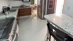 Eine moderne Küche mit Herd, Mikrowelle und Kühlschrank, ein Essbereich mit Tisch und Stühlen sowie ein Schild, das ein Hauptschlafzimmer kennzeichnet.