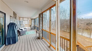 Eine überdachte Terrasse mit Essbereich, Steinpfeiler und großen Fenstern.