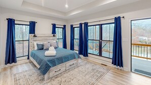 Ein Schlafzimmer mit einem großen Bett, einem Holzkopfstück und Blick auf eine Terrasse durch große Fenster.