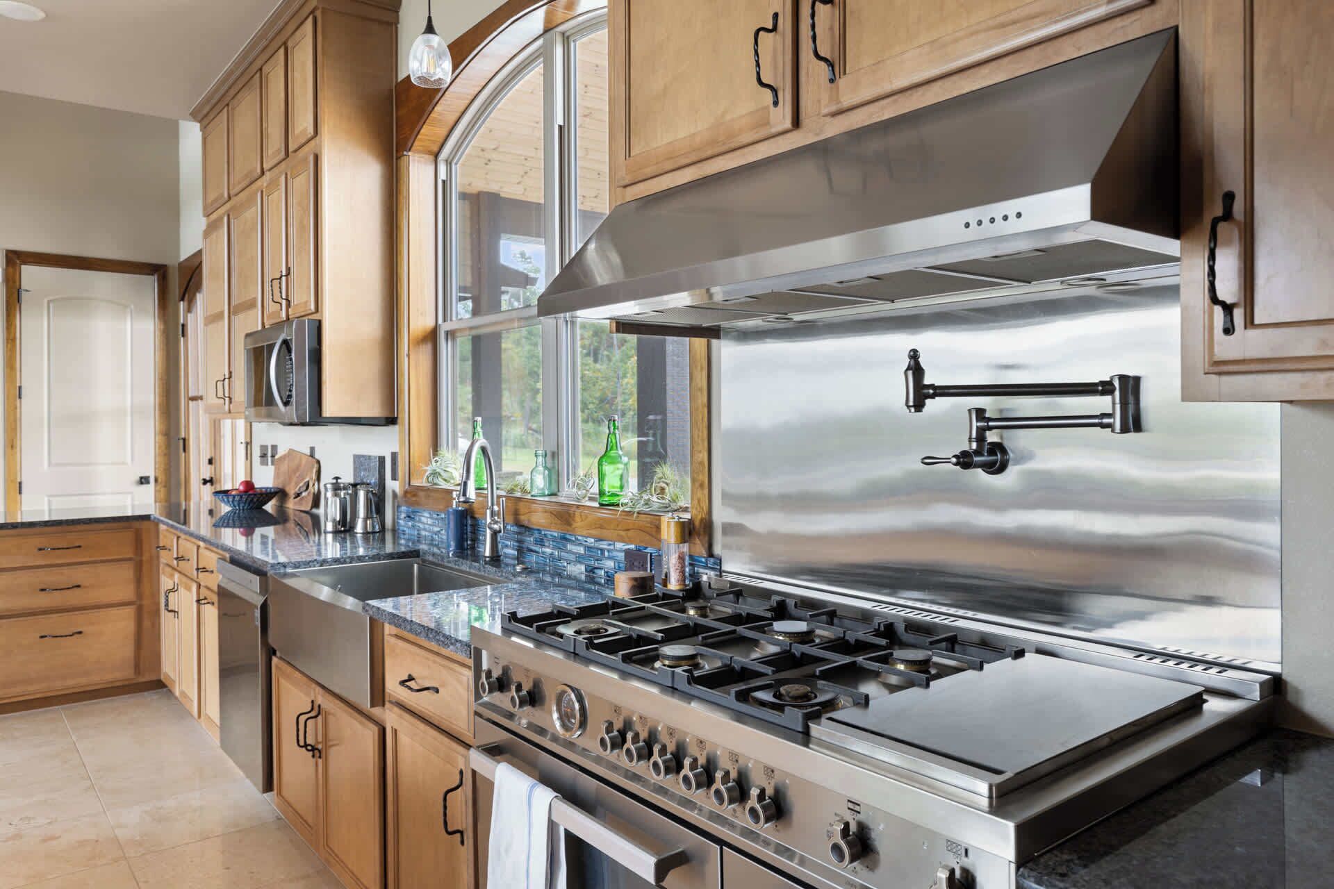 A modern kitchen with stainless steel appliances, wooden cabinets, and a large window.