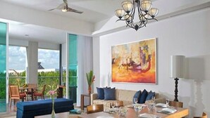 Uma sala de estar ampla com área de jantar, janelas grandes e um quadro na parede.