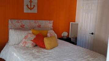 A bedroom with a bed, a ceiling fan, an anchor decoration, and a door.