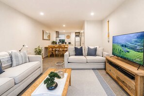 Uma sala de estar moderna com sofá, mesa de centro e televisão.