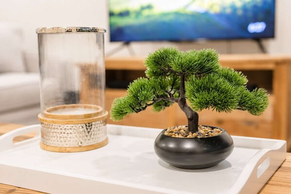 A bonsai tree in a black pot on a white tray with a decorative glass container beside it. - Salisbury Garden | 2BR with Parking | CBD (Christchurch)
