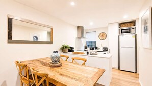 A compact kitchen with a dining area, a microwave, a clock, and a refrigerator. - Salisbury Garden | 2BR with Parking | CBD (Christchurch)