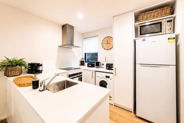 A modern kitchen with a stainless steel sink, a built-in oven, a microwave, and a refrigerator.