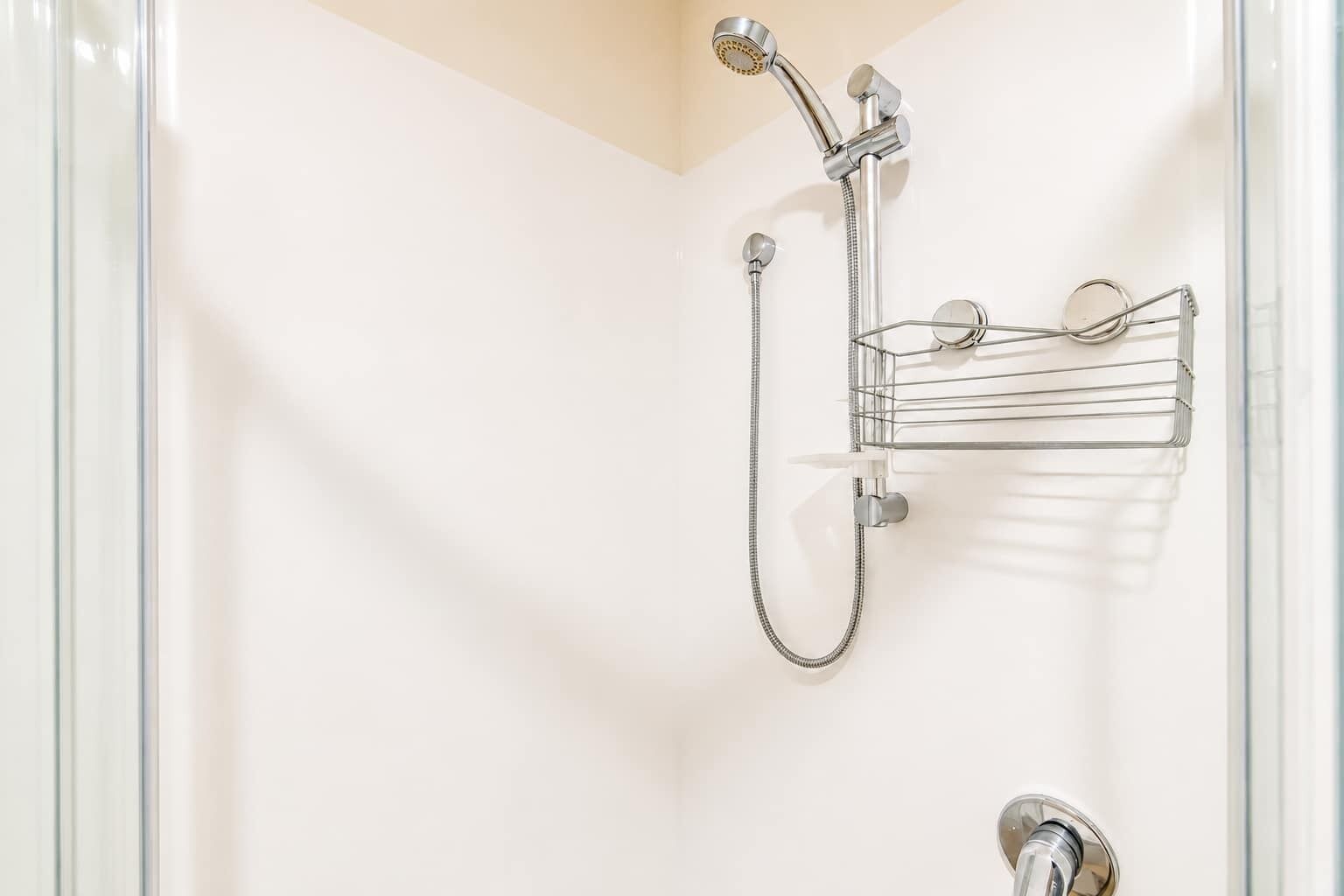 A shower with a handheld showerhead, a wall-mounted faucet, and a towel rack.