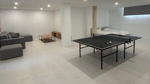 Ett modernt vardagsrum med ett bordtennisbord, en soffa och en säng.