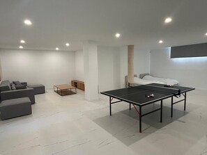 Ein modernes Wohnzimmer mit Tischtennisplatte, einer Couch und einem Bett.