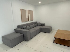 A modern living room with a sectional sofa, a wooden coffee table, and a framed picture on the wall. - Villa Sotogrande- Sleeps 10 - Pool Access- jacuzzi (San Roque)