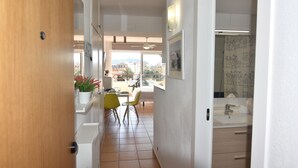 A hallway leading to a dining area with chairs and a table, a kitchen area with cabinets, and a bathroom with a shower curtain. - Discover this charming studio located in Santa Margarita, Roses! (Roses)