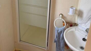 Un baño con mampara de vidrio, lavamanos y un perchero para toallas.