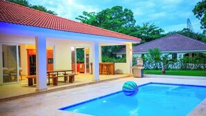 Una casa con piscina, patio coperto e tetto in tegole rosse.