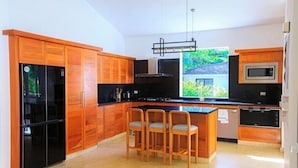 Una cucina moderna con mobili in legno, un frigorifero nero, un forno a microonde e un'area pranzo con sedie.