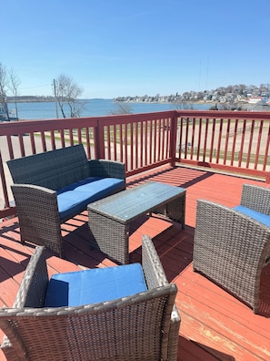 A deck with wicker furniture and a view of a lake.