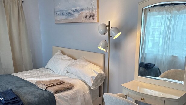 Ein Schlafzimmer mit Bett, Nachttisch, Stuhl und einem Bild an der Wand.