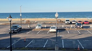 Ein Parkplatz mit Autos, einem Stoppschild und Blick auf das Meer.