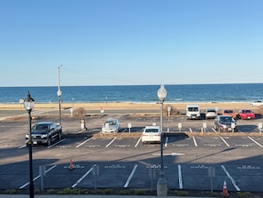 A parking lot with cars, a stop sign, and a view of the ocean.