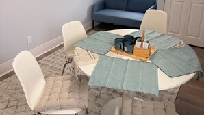 Ein Essbereich mit einem Tisch für vier Personen, einem blauen Sofa und einem Gemälde mit Strandmotiv.