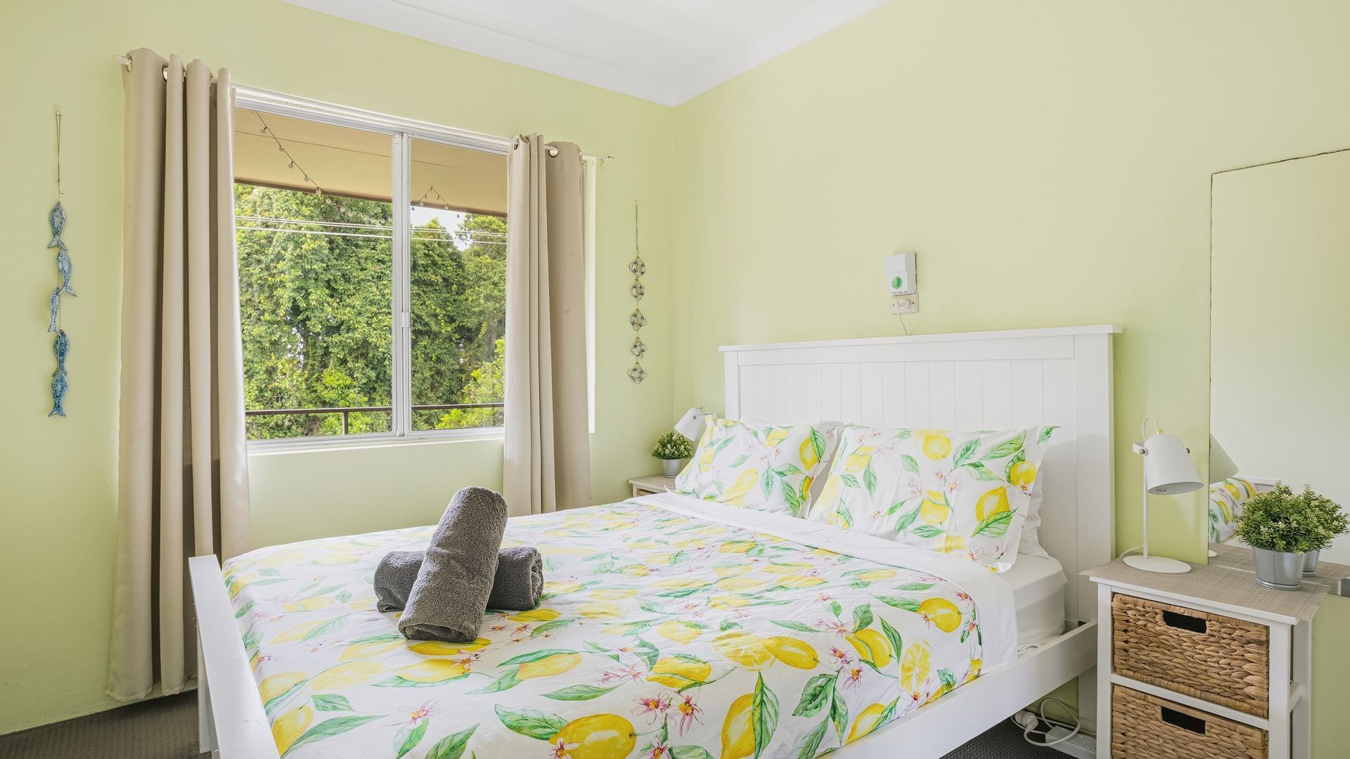 A bed with a floral bedspread, a bedside lamp, and a window with curtains.