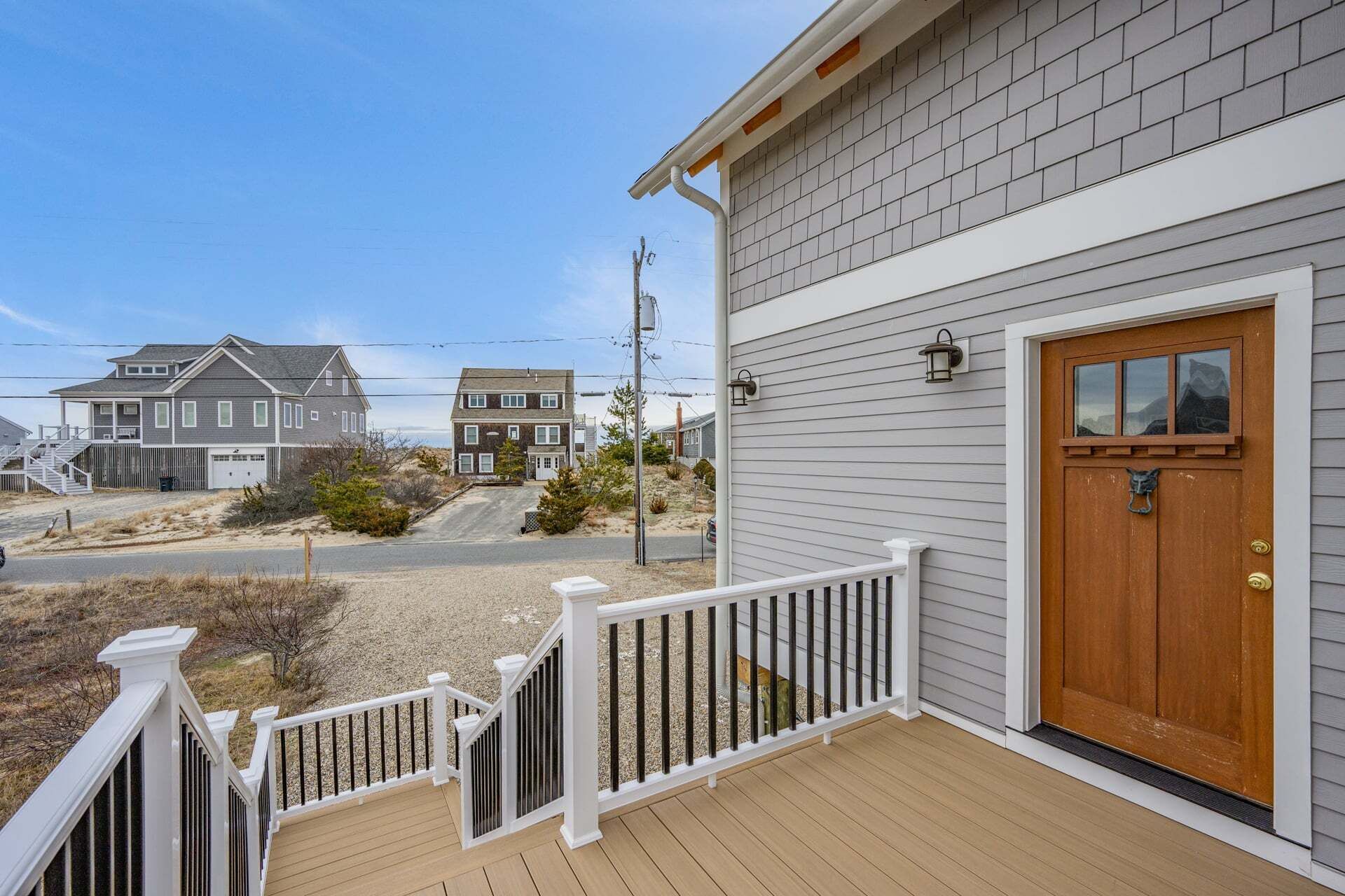 A residential property with a wooden deck, a white railing, and a front door with a window above it.
