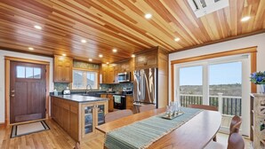 Eine Küche mit Holzausstattung, einem Edelstahlkühlschrank und einem Essbereich mit Tisch und Stühlen.