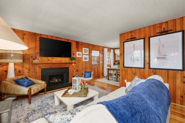 A cozy living room with a fireplace, a television, and framed pictures on the wall.