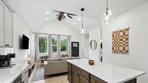 Eine moderne Küche mit einer großen Kochinsel, einem Deckenventilator und einer karierten Wanddekoration.