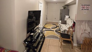 Una sala de estar con televisor, sofá, mesa de comedor y una silla.