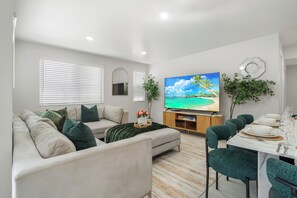 Una sala de estar moderna con sofá, televisor, mesa de comedor y sillas.