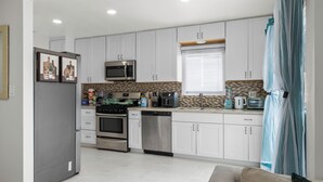 A modern kitchen with white cabinets, stainless steel appliances, and a herringbone tile backsplash. - Ranch-Style w Gated Yard, 4 Parking, 4 Bedroom 3 Bathroom (La Mesa)