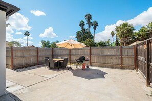 A backyard with a patio table, chairs, a grill, and an umbrella. - Ranch-Style w Gated Yard, 4 Parking, 4 Bedroom 3 Bathroom (La Mesa)