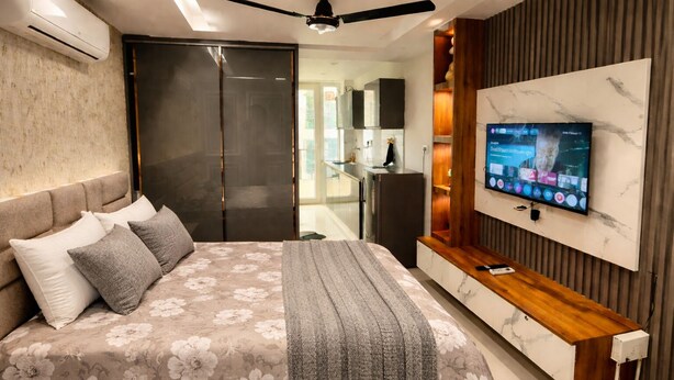 Ein modernes Schlafzimmer mit einem großen Bett, einem an der Wand montierten Fernseher und einem Holzkonsolentisch.