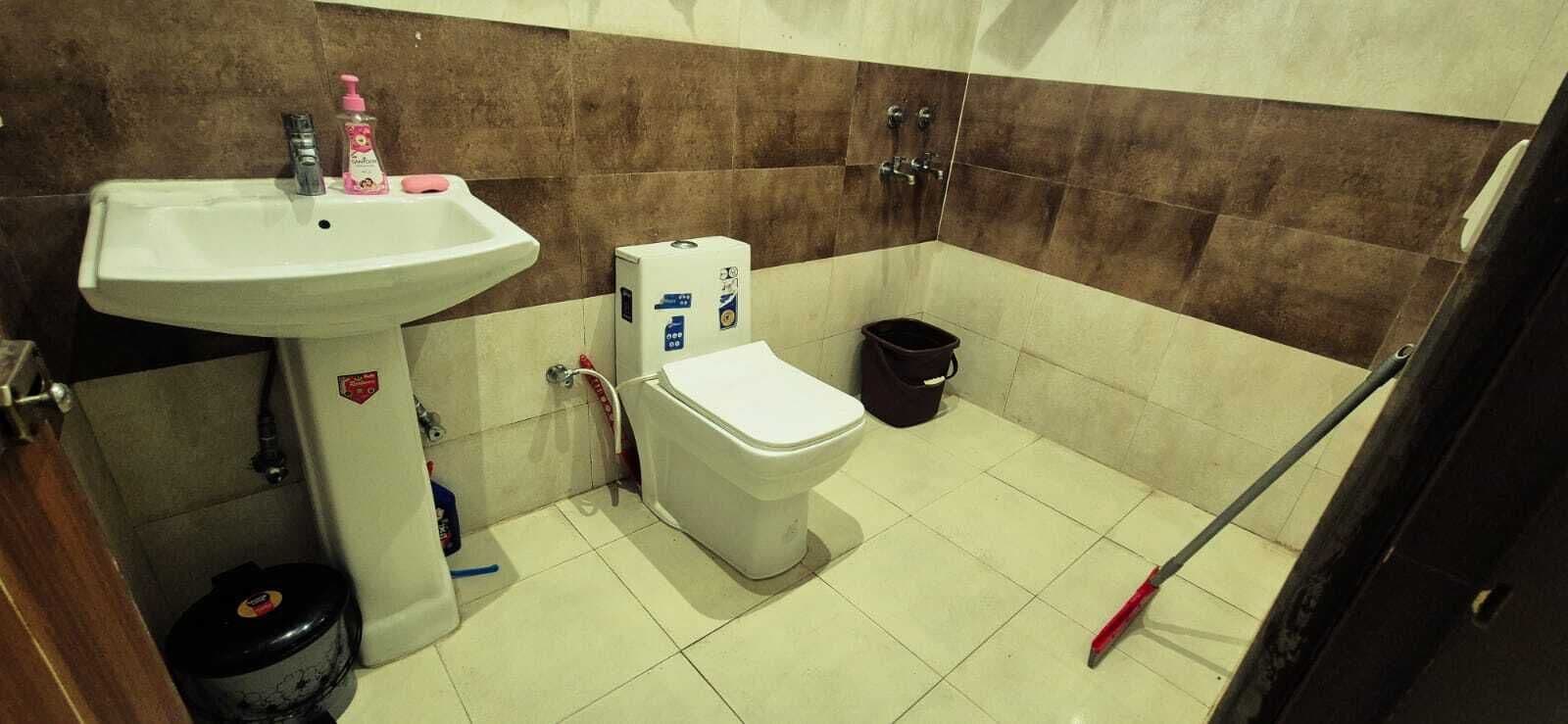 Ein Badezimmer mit Waschbecken, Toilette und einem Mopp.