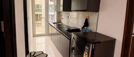 A modern kitchen with a refrigerator, a washing machine, and a window.